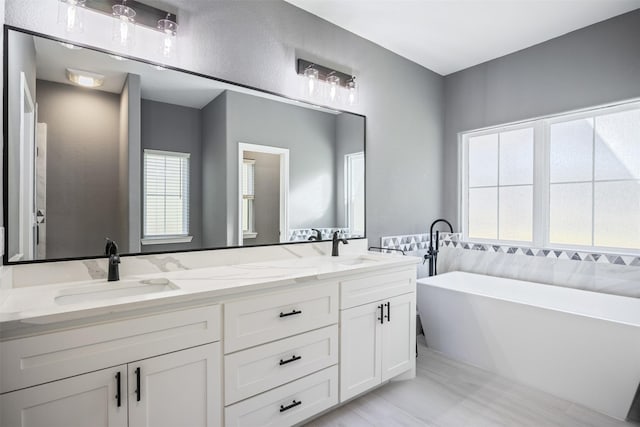 bathroom with double vanity, a freestanding tub, and a sink