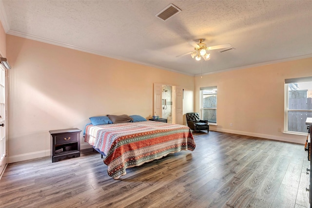 bedroom with visible vents, crown molding, a textured ceiling, and wood finished floors