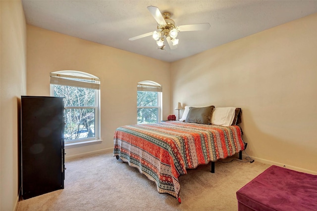 bedroom with ceiling fan, baseboards, and light colored carpet