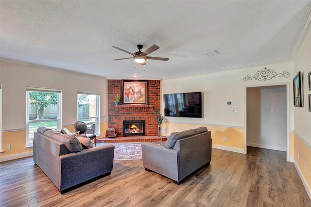 living room with a textured ceiling, a brick fireplace, wood finished floors, and visible vents