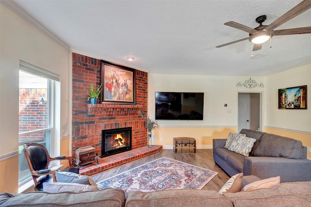 living area featuring ornamental molding, a brick fireplace, a textured ceiling, and wood finished floors