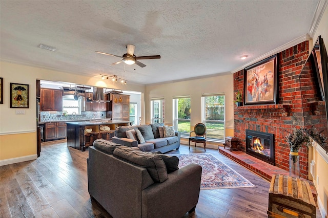 living area featuring dark wood-style floors, a brick fireplace, visible vents, and ornamental molding