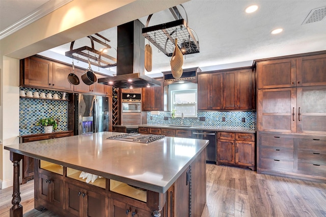 kitchen featuring a center island, island exhaust hood, stainless steel appliances, visible vents, and decorative backsplash