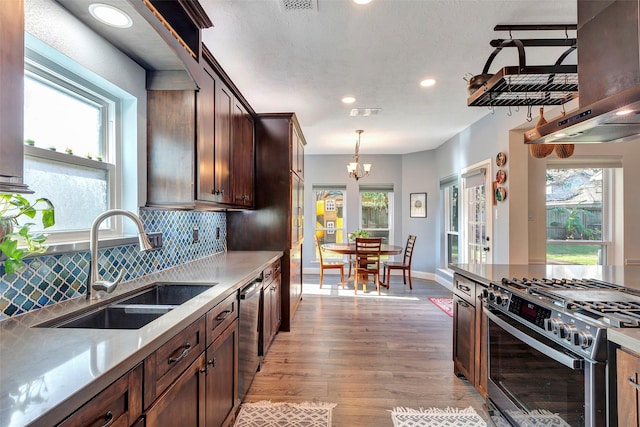 kitchen featuring stainless steel appliances, pendant lighting, light countertops, and a sink