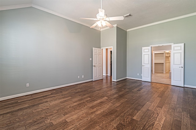 unfurnished bedroom featuring baseboards, visible vents, dark wood-style floors, ornamental molding, and a spacious closet