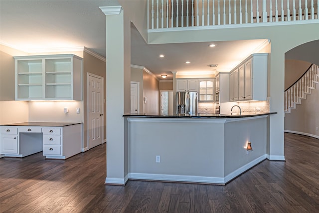 kitchen featuring stainless steel refrigerator with ice dispenser, dark countertops, ornamental molding, dark wood-type flooring, and white cabinetry