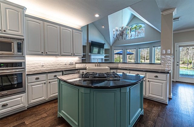 kitchen with stainless steel appliances, dark countertops, a peninsula, and white cabinetry