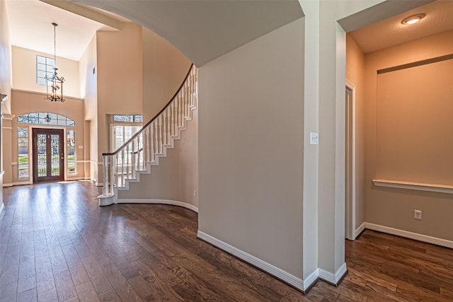 foyer entrance featuring an inviting chandelier, stairs, baseboards, and dark wood-style flooring