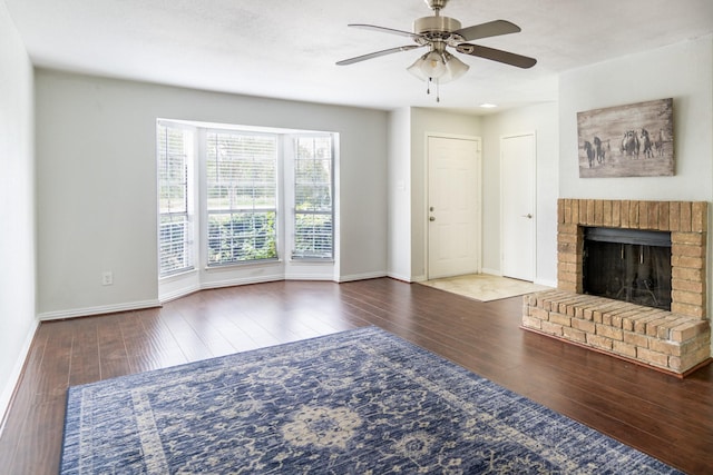 unfurnished living room with dark hardwood / wood-style flooring, a brick fireplace, and ceiling fan