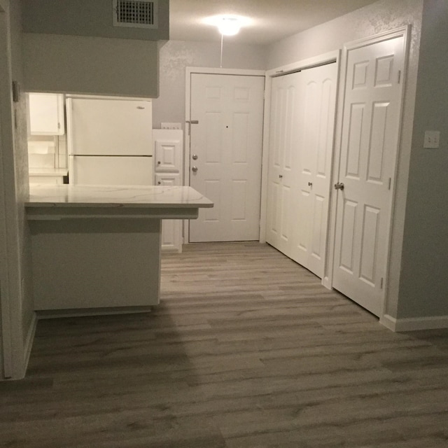 kitchen featuring a kitchen breakfast bar, dark hardwood / wood-style floors, kitchen peninsula, and white refrigerator