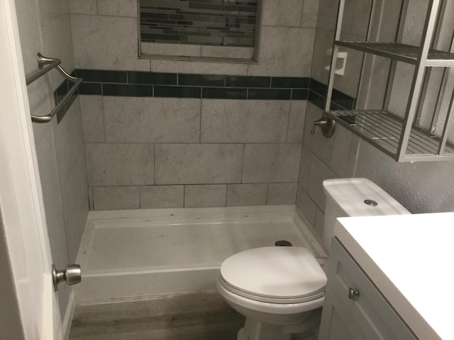 bathroom featuring vanity, a tile shower, toilet, and hardwood / wood-style floors