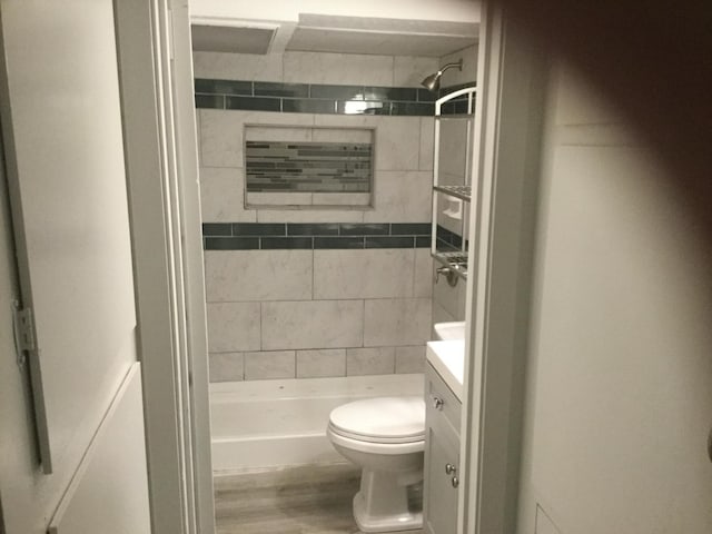 bathroom with hardwood / wood-style floors, a tile shower, vanity, and toilet