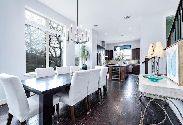 dining room with visible vents, dark wood-style flooring, a chandelier, and beverage cooler
