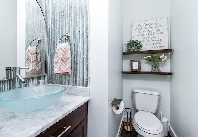 bathroom featuring toilet, vanity, and baseboards