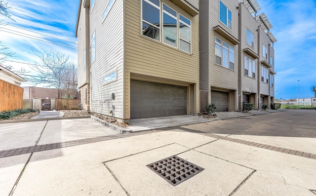 exterior space featuring a garage, fence, and driveway