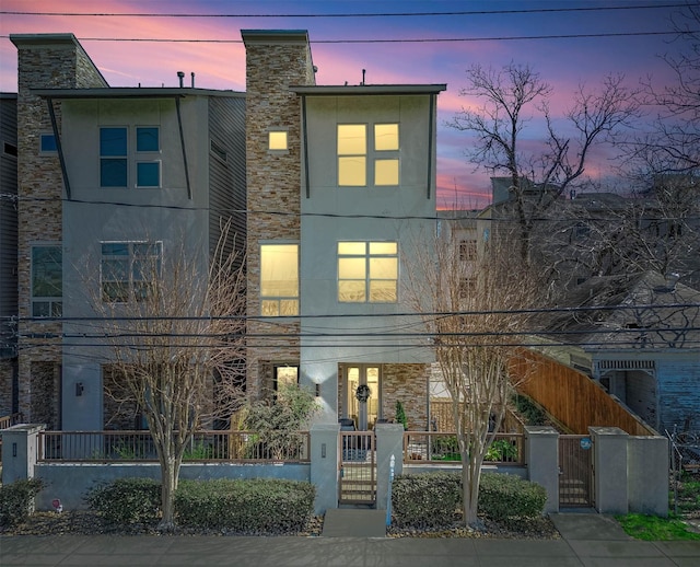 contemporary house with a gate, stucco siding, and stone siding