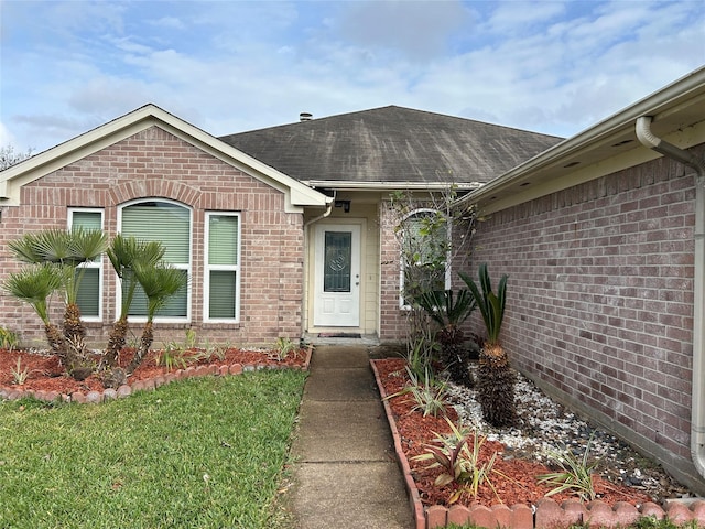 view of exterior entry featuring a lawn