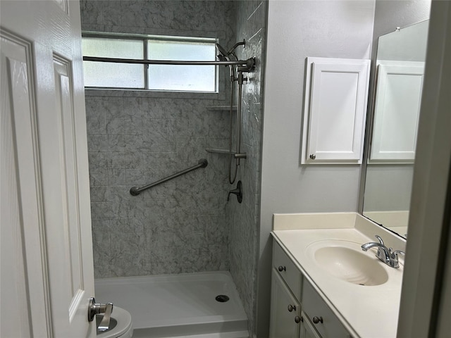 bathroom with tiled shower and vanity