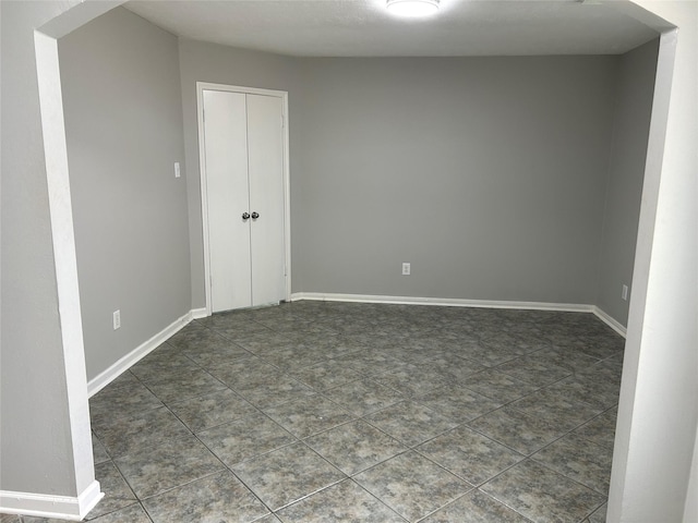 unfurnished bedroom featuring a closet and dark tile patterned flooring