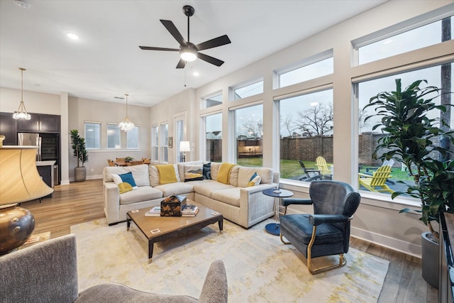 living room with ceiling fan with notable chandelier and wood-type flooring