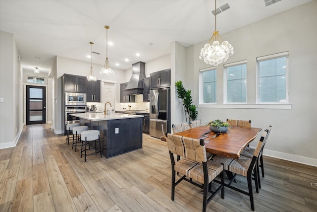 dining room with sink, a chandelier, and light hardwood / wood-style floors