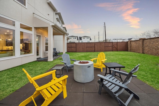 patio terrace at dusk featuring a yard and an outdoor fire pit