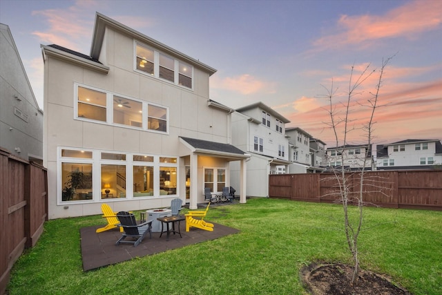 back house at dusk featuring a patio area and a yard