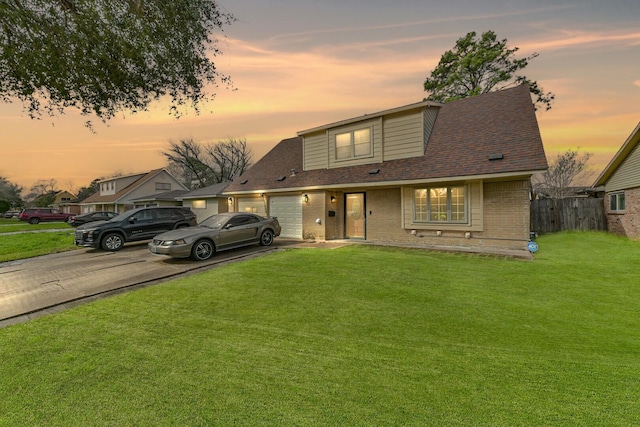 view of front of house with brick siding, a front lawn, fence, a garage, and driveway