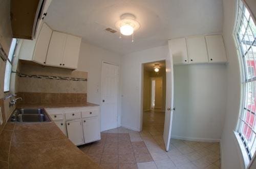 kitchen featuring sink, backsplash, and white cabinets