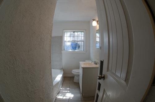 bathroom featuring tile patterned floors, vanity, toilet, and a tub