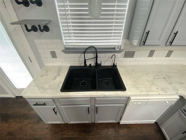 kitchen with tasteful backsplash, dishwasher, sink, and white cabinets