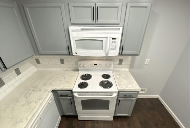 kitchen featuring white appliances, dark hardwood / wood-style flooring, gray cabinets, and backsplash