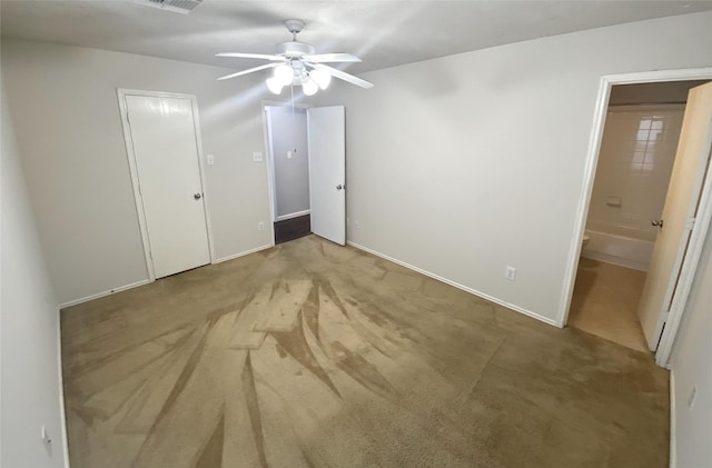 unfurnished bedroom featuring ceiling fan, light colored carpet, and ensuite bathroom