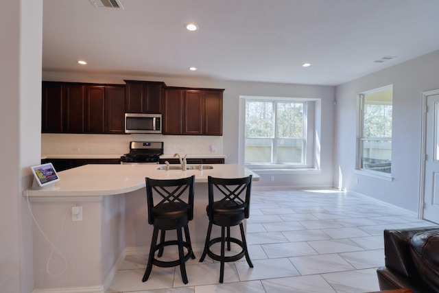 15158 N Heron Heights Way, Magnolia, TX 77354 - kitchen with a kitchen breakfast bar, light countertops, tasteful backsplash, a sink, and appliances with stainless steel finishes