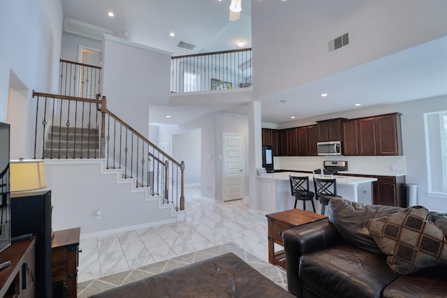 15158 N Heron Heights Way, Magnolia, TX 77354 - living room with visible vents, baseboards, a high ceiling, and stairway