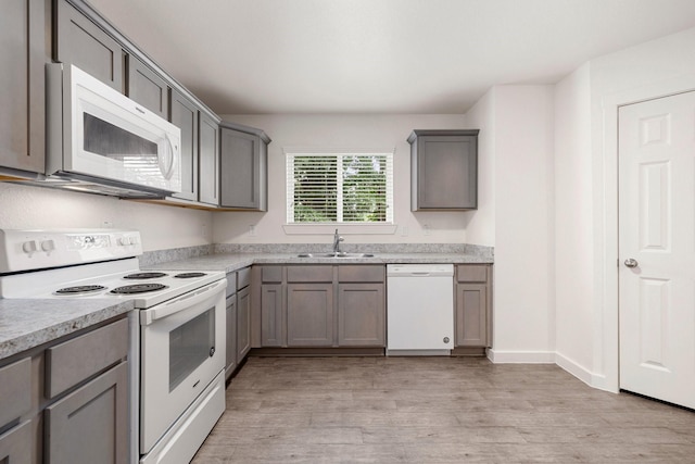 kitchen featuring gray cabinetry, sink, white appliances, and light hardwood / wood-style floors