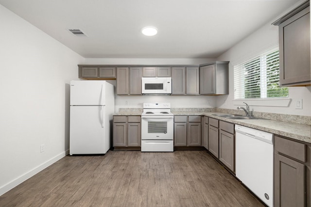 kitchen featuring sink, white appliances, gray cabinets, and light wood-type flooring