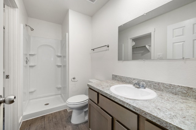 bathroom featuring hardwood / wood-style flooring, toilet, vanity, and walk in shower