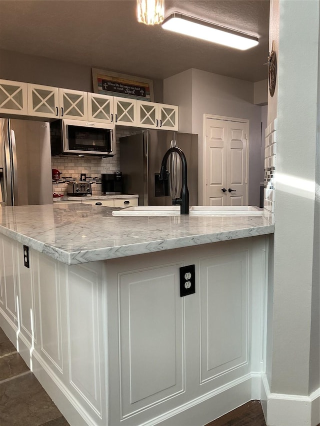 kitchen featuring appliances with stainless steel finishes, decorative backsplash, light stone counters, and white cabinets