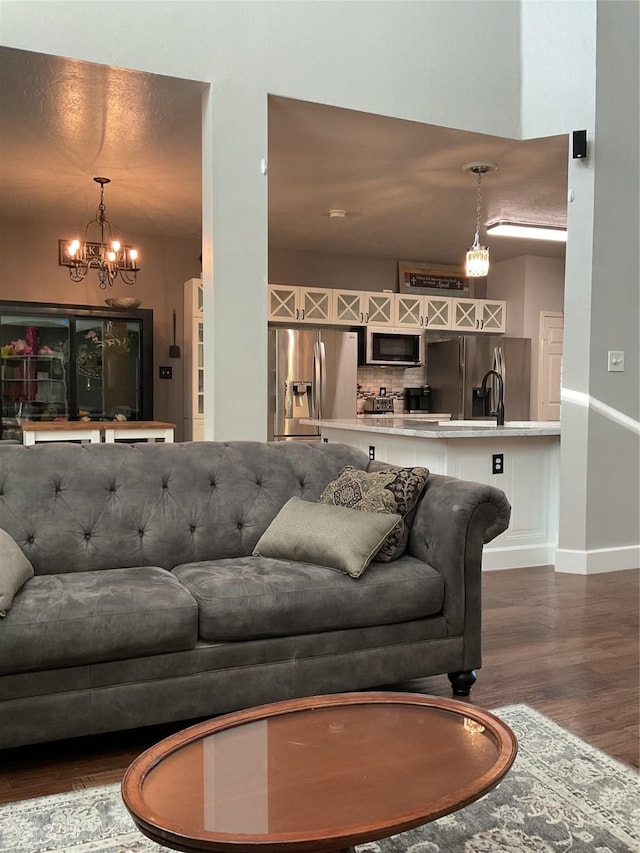 living room featuring sink, dark wood-type flooring, and an inviting chandelier