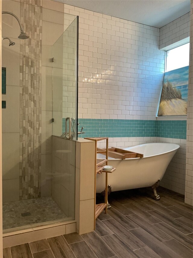 bathroom with tile walls and separate shower and tub