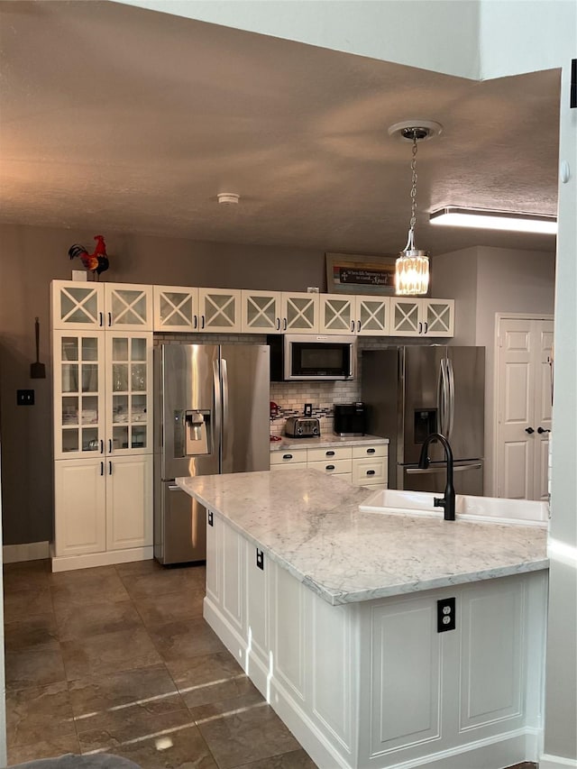 kitchen featuring stainless steel appliances, hanging light fixtures, light stone countertops, tasteful backsplash, and white cabinets