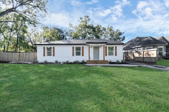 view of front facade with board and batten siding, a front yard, and fence