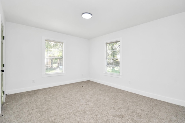 empty room featuring a healthy amount of sunlight, light carpet, and baseboards