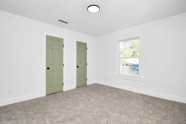 unfurnished bedroom featuring carpet floors, visible vents, and baseboards