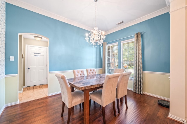 dining space featuring visible vents, arched walkways, dark wood finished floors, and ornamental molding