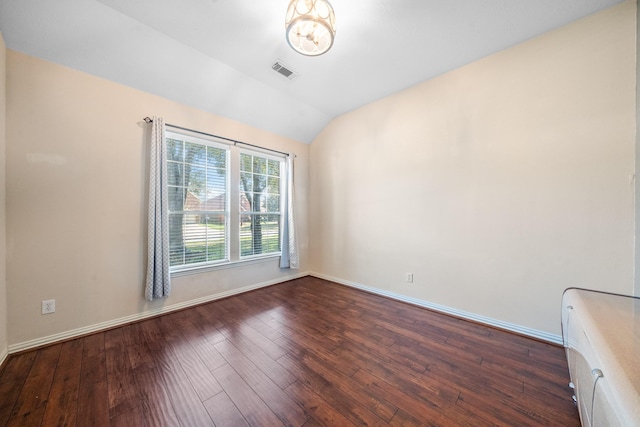 spare room with vaulted ceiling, visible vents, dark wood finished floors, and baseboards