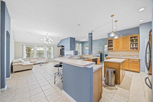 kitchen with a breakfast bar area, light countertops, glass insert cabinets, open floor plan, and an island with sink