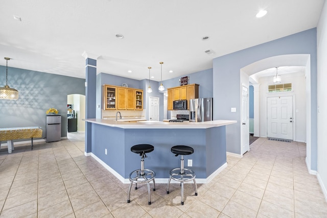 kitchen with arched walkways, black microwave, light countertops, stainless steel fridge with ice dispenser, and pendant lighting