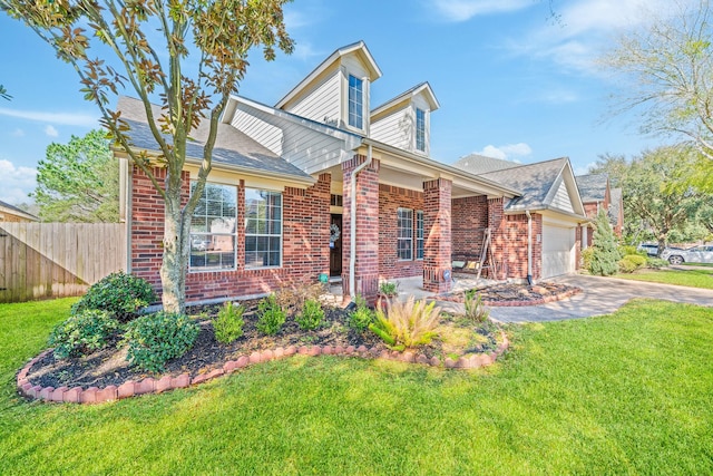 view of front of house with a garage, brick siding, a front yard, and fence